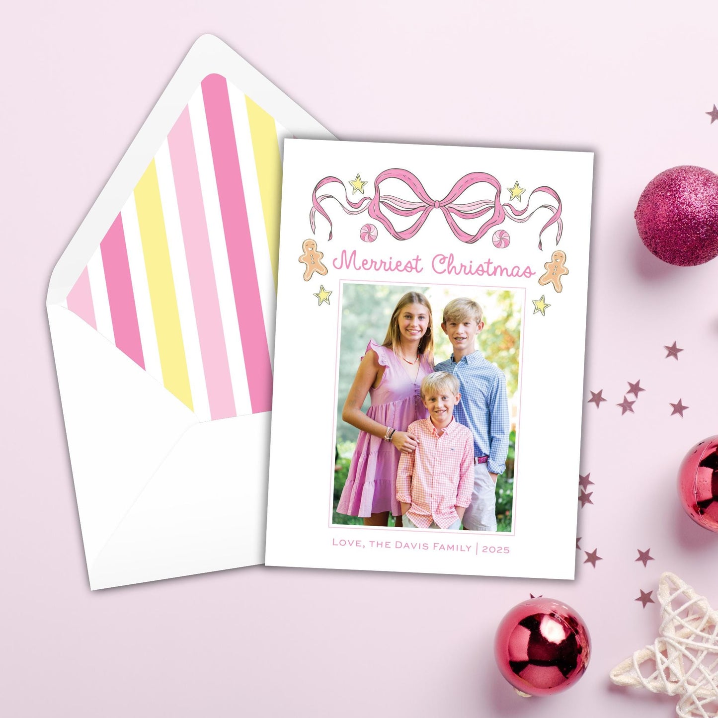 A Christmas card with a photo of three children and the text "Merry Christmas" is displayed next to an envelope with a pink and yellow striped pattern.