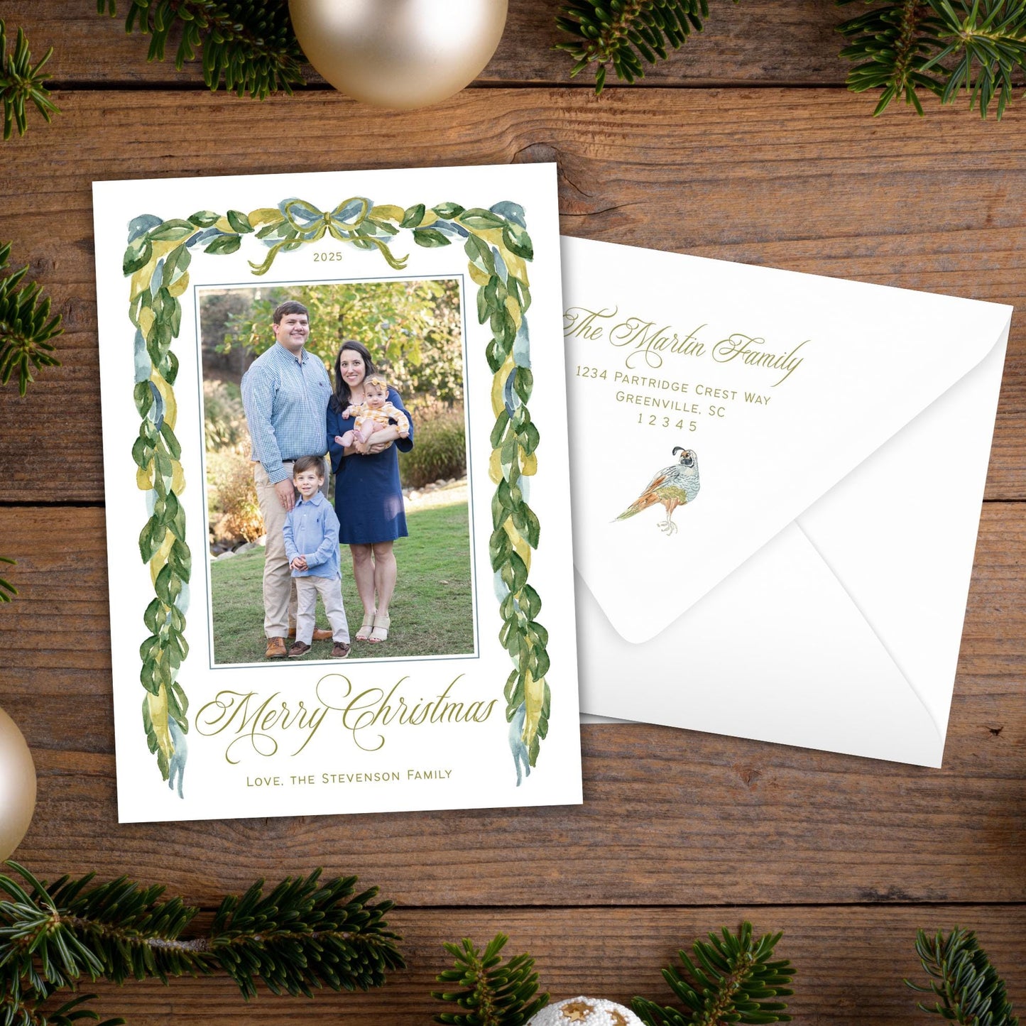 A 2020 family photo is displayed on a white card with a green border, placed on a wooden surface surrounded by Christmas decorations.