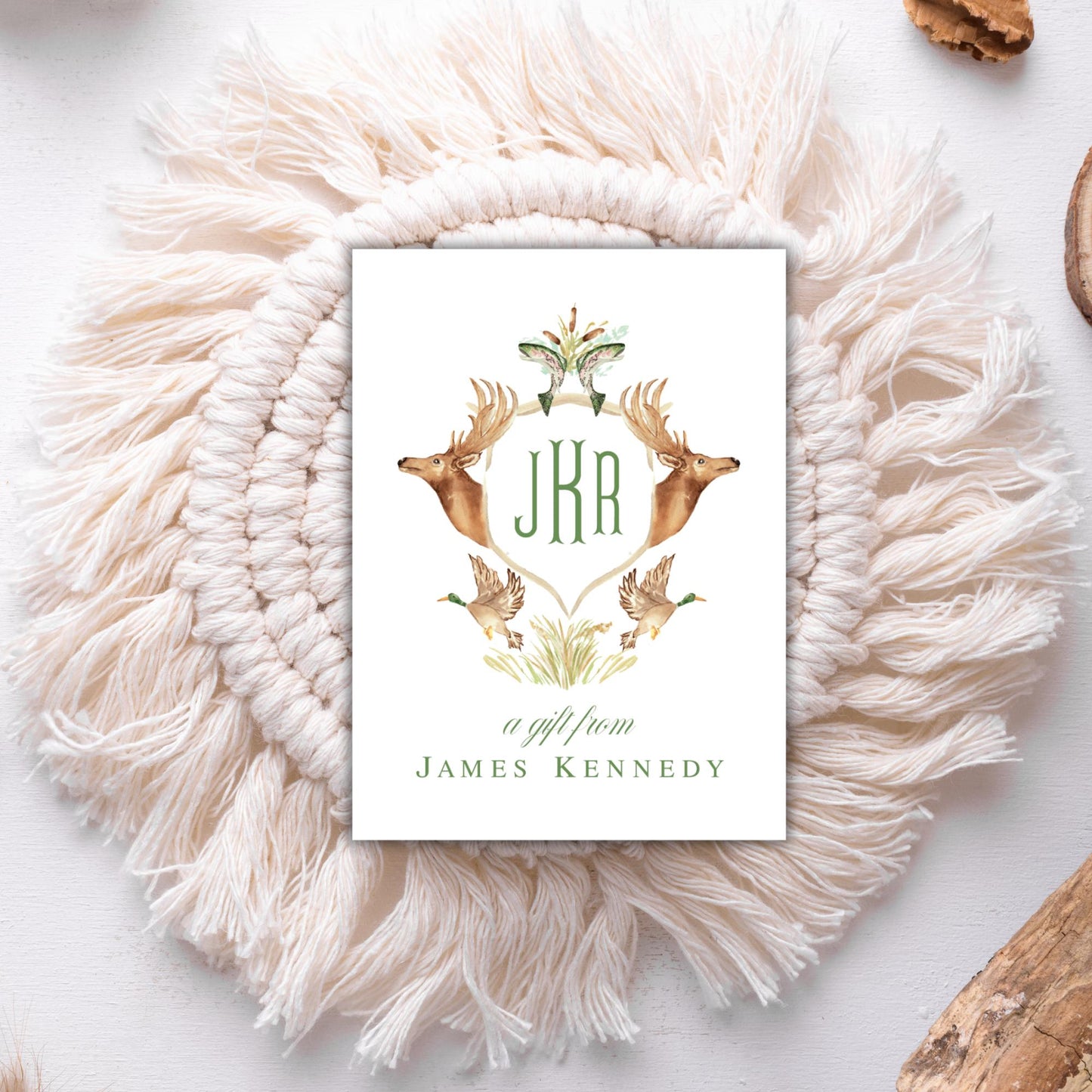 A white card with a decorative border featuring a deer and two birds, surrounded by a white shawl.