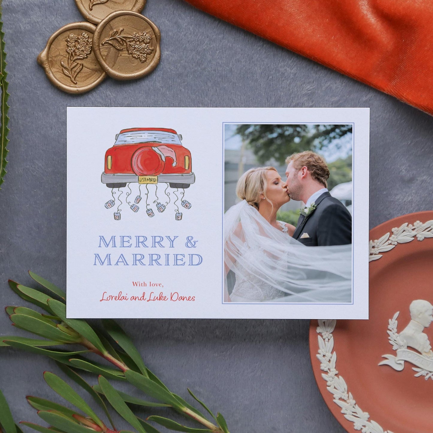 A wedding card featuring a couple embracing, with a red car and a photo of the couple. The card also includes a message that reads "Merry & Married" and a personal note that says "With love, Loraie and Luke Davis".