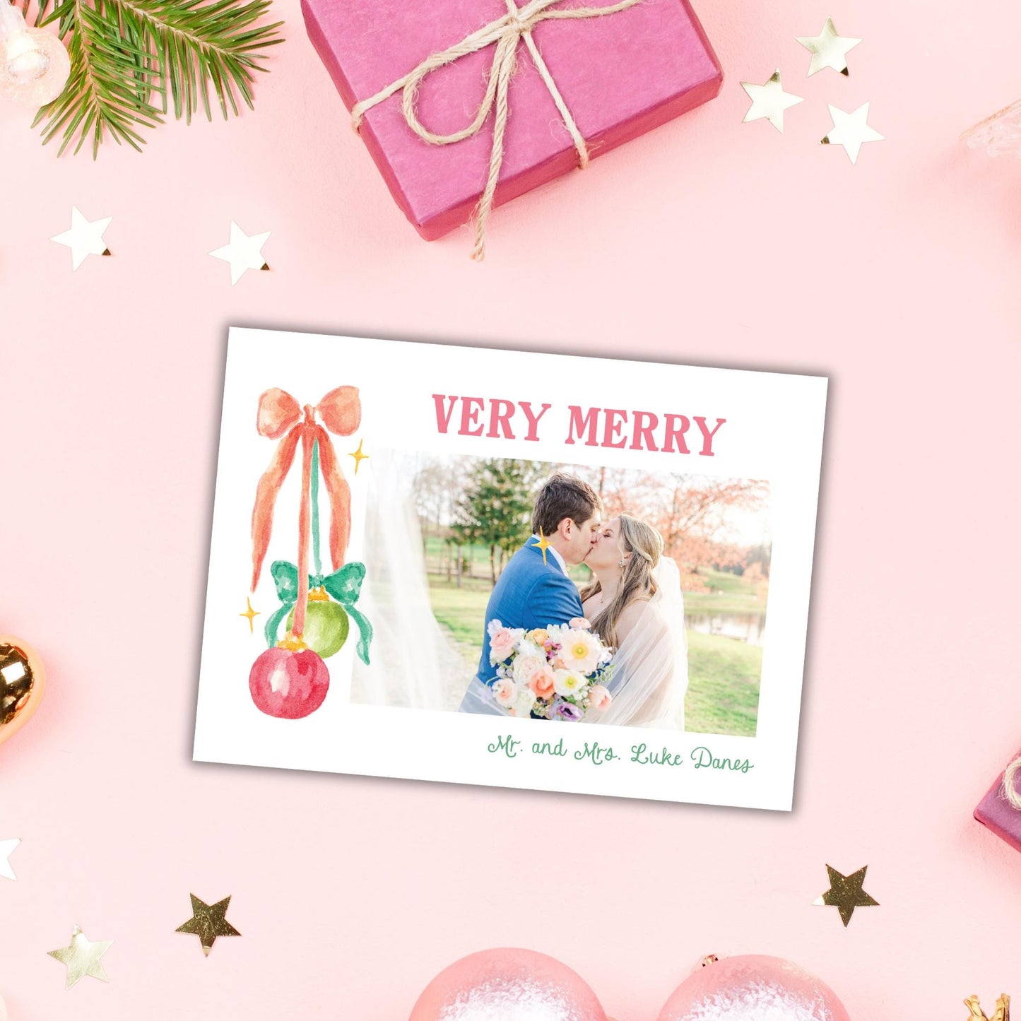 A pink gift box with a bow, a couple embracing, and a photo of the couple is displayed on a pink background with Christmas ornaments and stars.