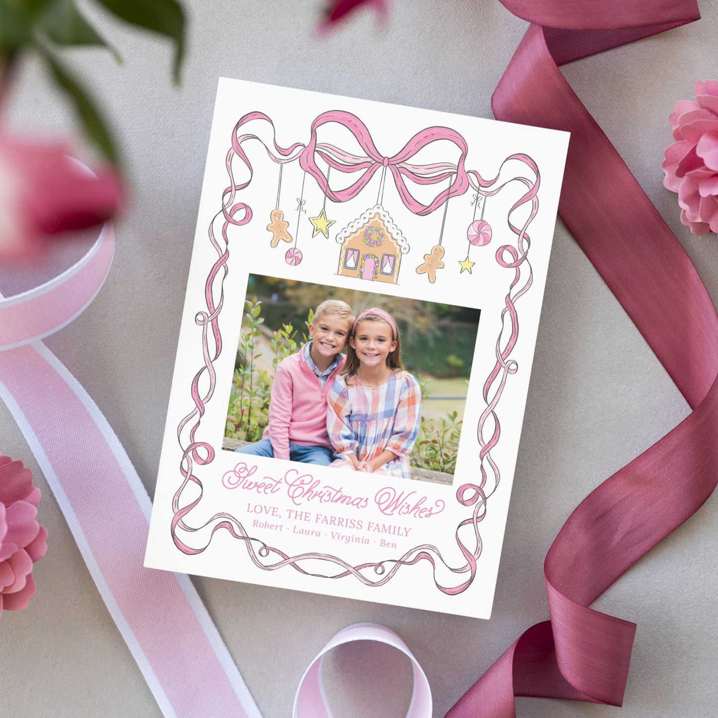A white card with a pink ribbon and a photo of two young girls, surrounded by pink flowers and a pink ribbon.