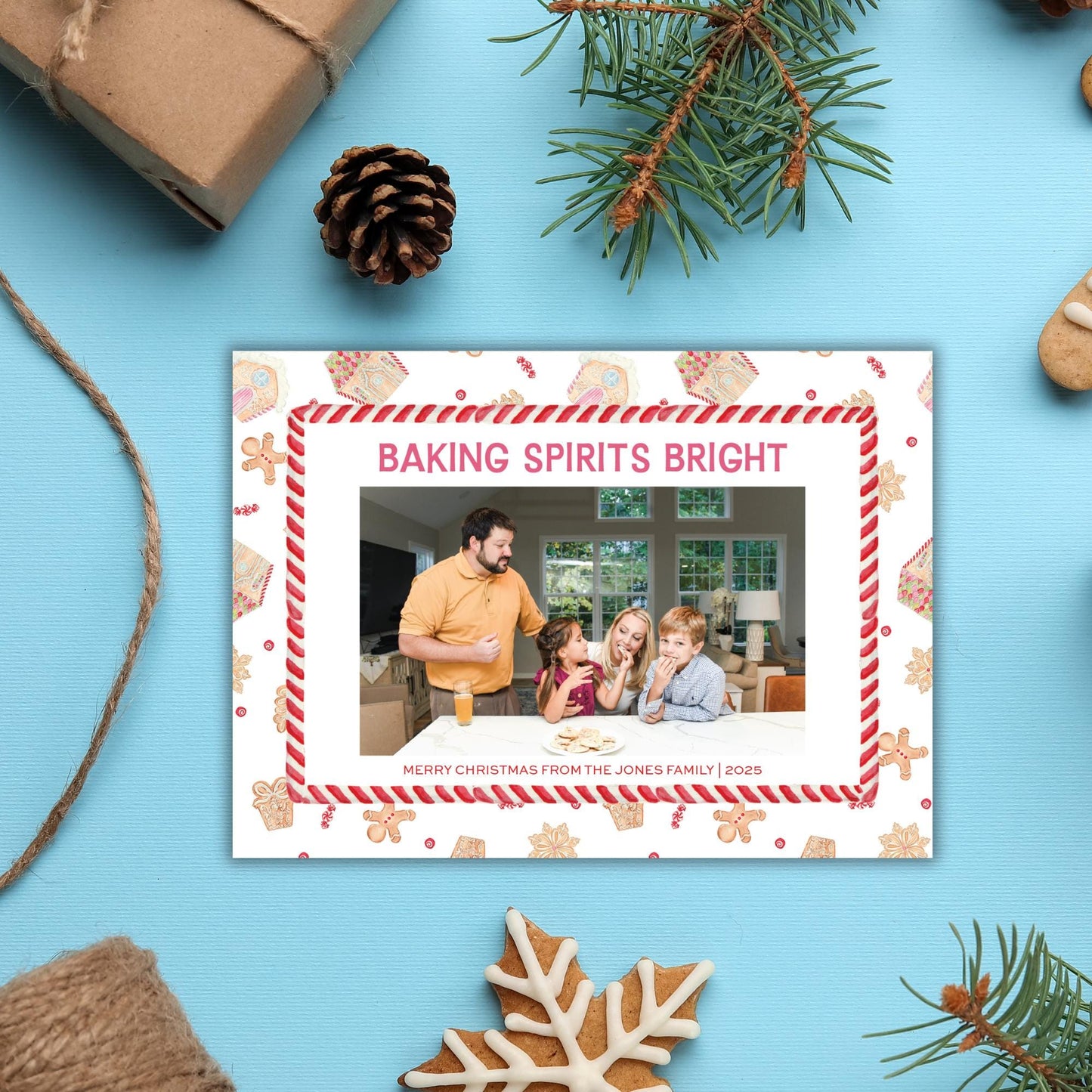 A framed photo of a family enjoying a holiday gathering, surrounded by festive decorations such as pine cones, gingerbread cookies, and a snowflake.