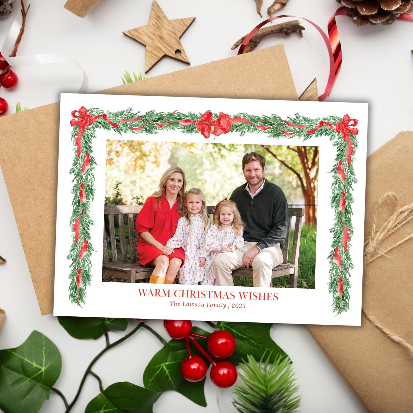 A family portrait of a man, woman, and two young girls, framed within a Christmas wreath and surrounded by holiday decorations such as pine cones, berries, and a star.