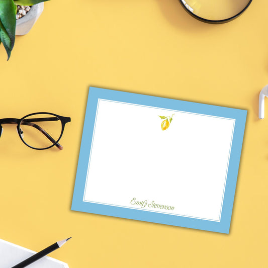 a blue-bordered notepad with a blank white page, a pair of glasses, and a pen on a yellow background.