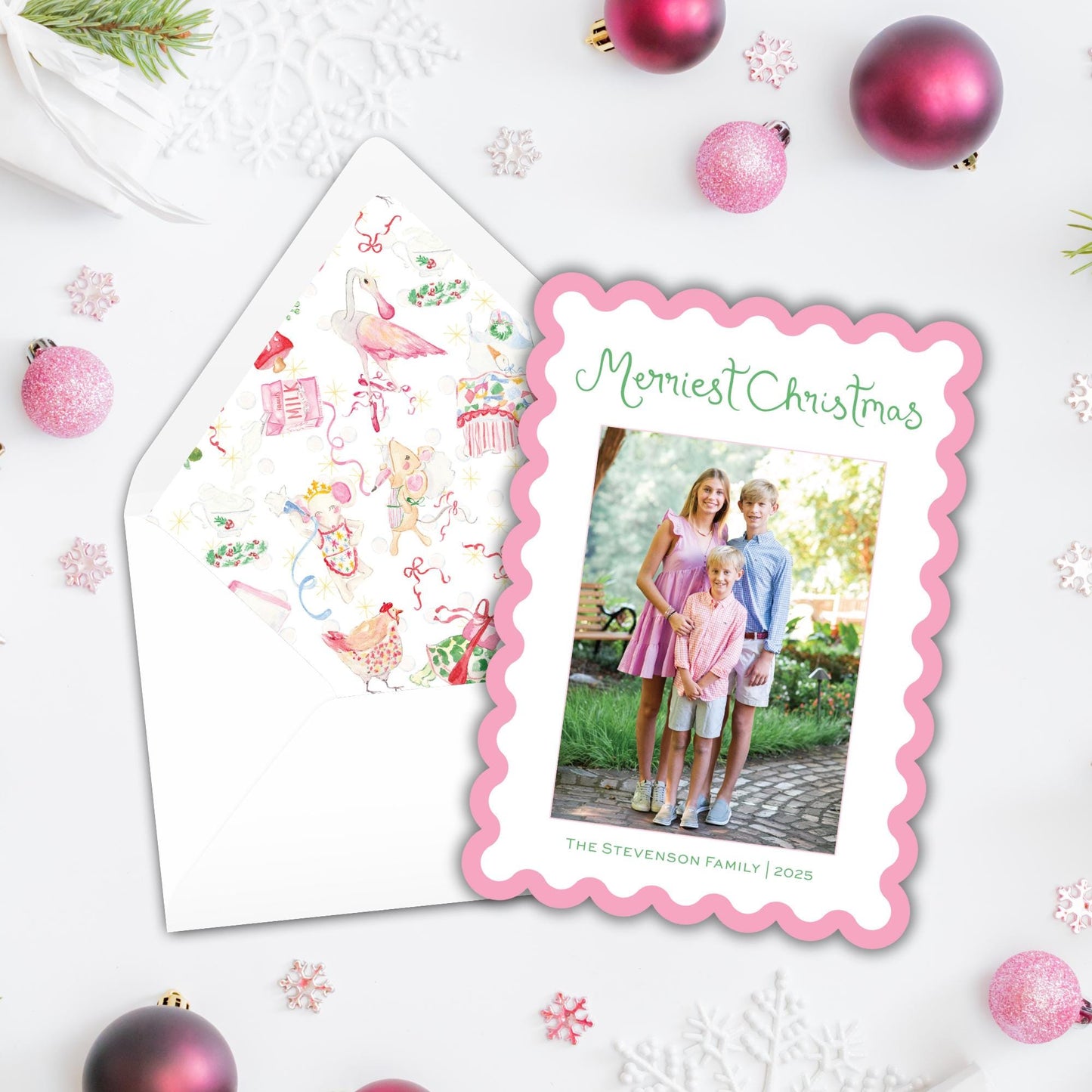 A Christmas card with a photo of three children and the text "Mermiest Christmas" is displayed next to an envelope with a patterned design.