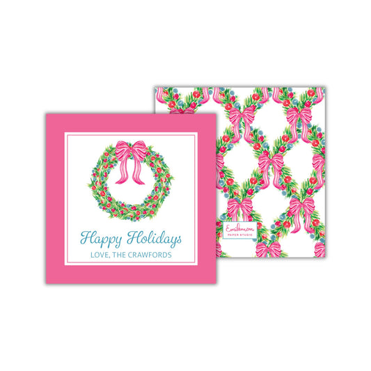 a pink greeting card with a wreath design and pink bows, along with a white square card featuring a repeating pattern of pink bows and green leaves.