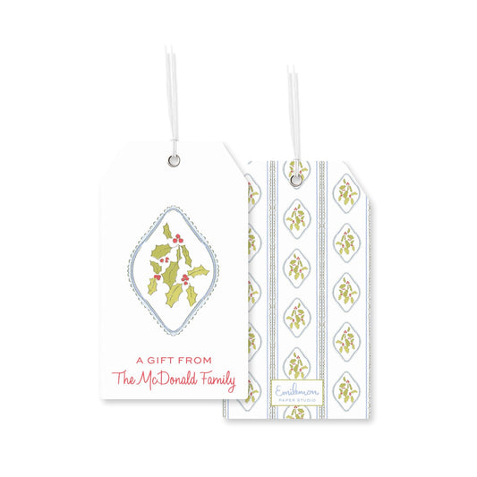 two white tags with Christmas-themed designs. The tag on the left has a holly and berries design, while the tag on the right has a repeating pattern of holly and berries. Both tags include a message that reads &quot;A gift from The McDonald Family&quot;.