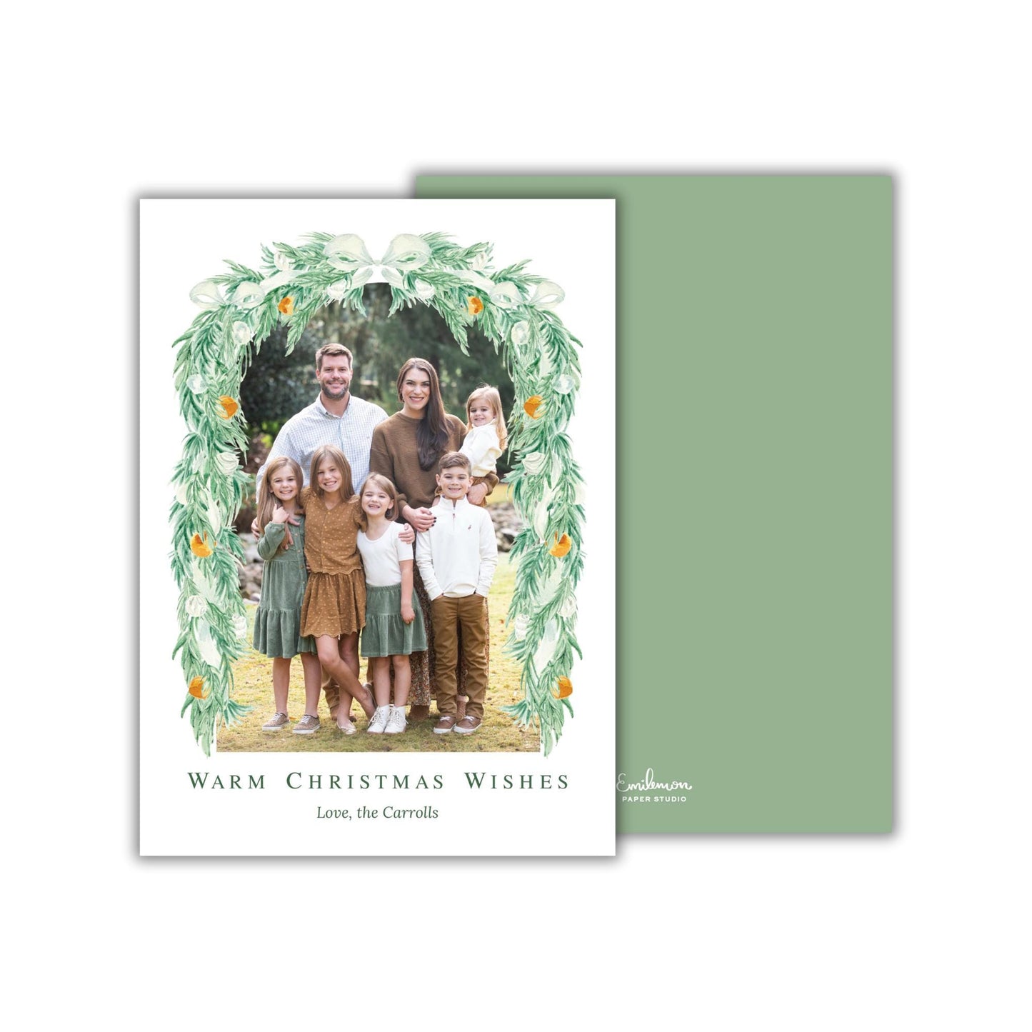 A family portrait of a man, woman, and children, surrounded by a wreath of greenery and orange flowers, with the text &quot;Warm Christmas Wishes&quot; and &quot;Love, the Carrots&quot; below the image.