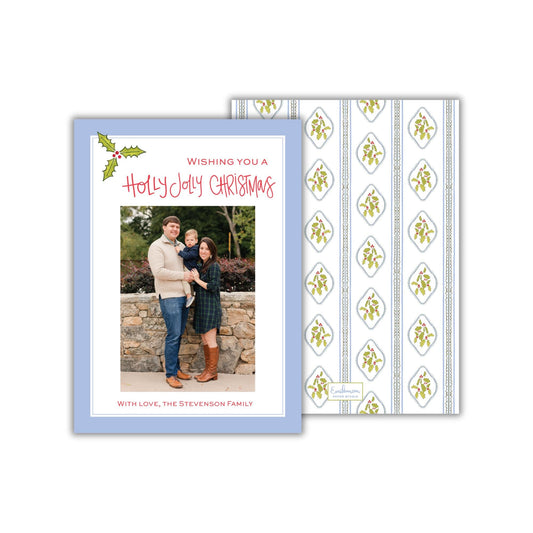 A holiday greeting card featuring a family photo of a man, woman, and child. The card has a blue background with a patterned design and a message wishing the recipient a Merry Christmas.