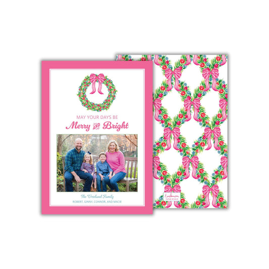 A pink and white holiday card featuring a family portrait and a wreath design. The card has a pink border and a floral pattern on the right side.