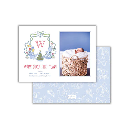 The image is a holiday card featuring a baby in a basket and a Christmas tree. The card has a festive design with a large letter "W" and a message that reads "Merry's cheer this year! The Walters family Brad, Jessica, and Henry (2 mo's)".