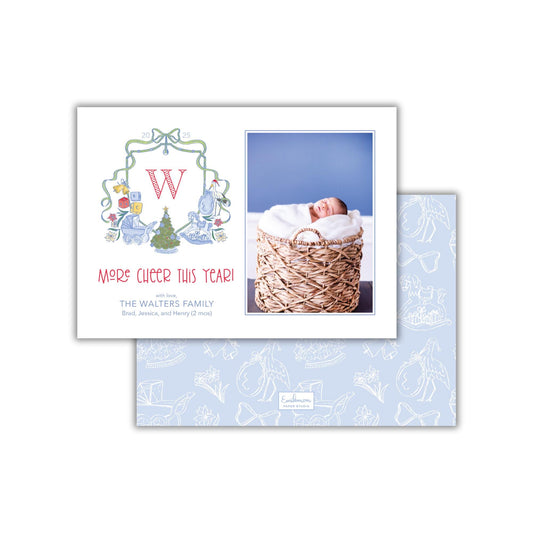 The image is a holiday card featuring a baby in a basket and a Christmas tree. The card has a festive design with a large letter &quot;W&quot; and a message that reads &quot;Merry&#39;s cheer this year! The Walters family Brad, Jessica, and Henry (2 mo&#39;s)&quot;.