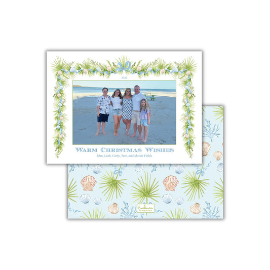 A family photo of a group of people standing together on a beach, with a floral border framing the image.