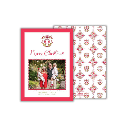 The image is a Christmas card featuring a family photo of a man, woman, and two children dressed in festive attire. The card has a red border and a repeating pattern of red and white flowers on the background.
