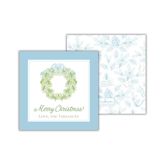 A blue greeting card with a wreath design and the text &quot;Merry Christmas&quot; and &quot;Love, the Terrances&quot; printed on it.