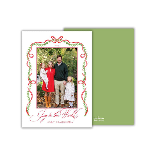 A family portrait of a man, woman, and two young girls, surrounded by a decorative border with red and green ribbons. The text on the card reads &quot;Joy to the World, Love, the Baker Family&quot;.