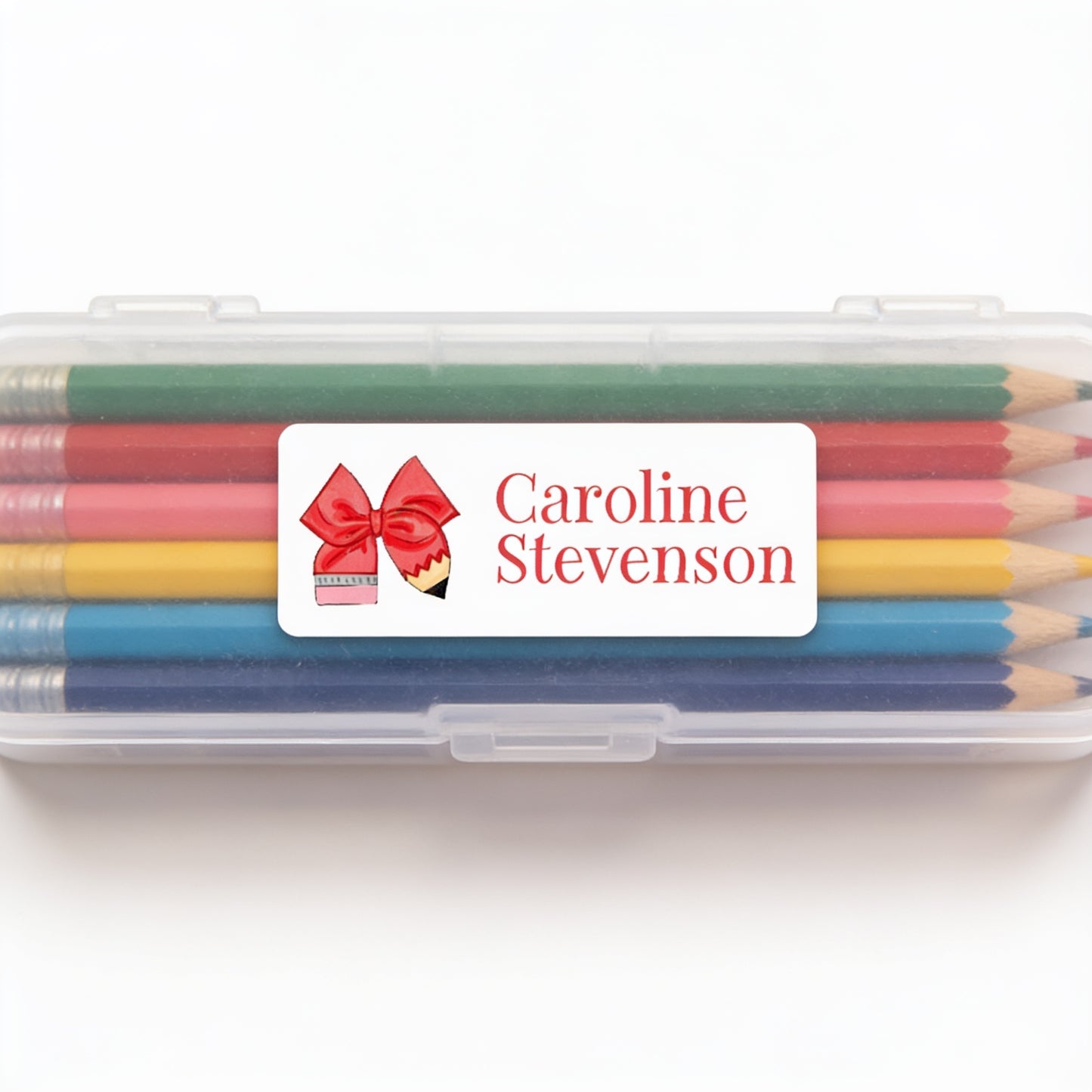 A clear plastic pencil case containing a set of colored pencils with a personalized label on it.