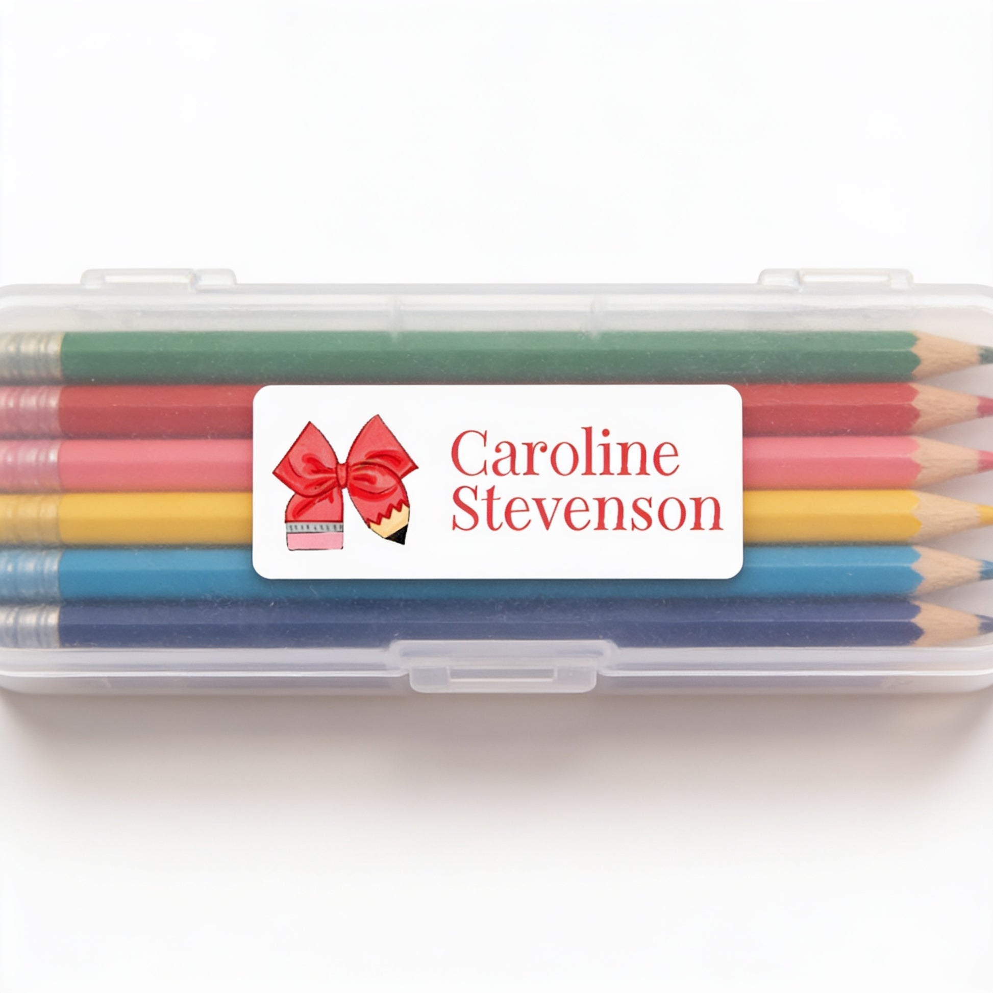 A clear plastic pencil case containing a set of colored pencils with a personalized label on it.