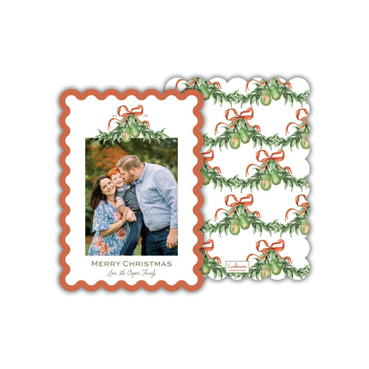 A Christmas card featuring a family photo with a pattern of green leaves and red ribbons.