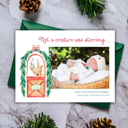 A Christmas card featuring a baby in a basket, with a reindeer illustration and a caption that reads "Not a creature was stirring..."