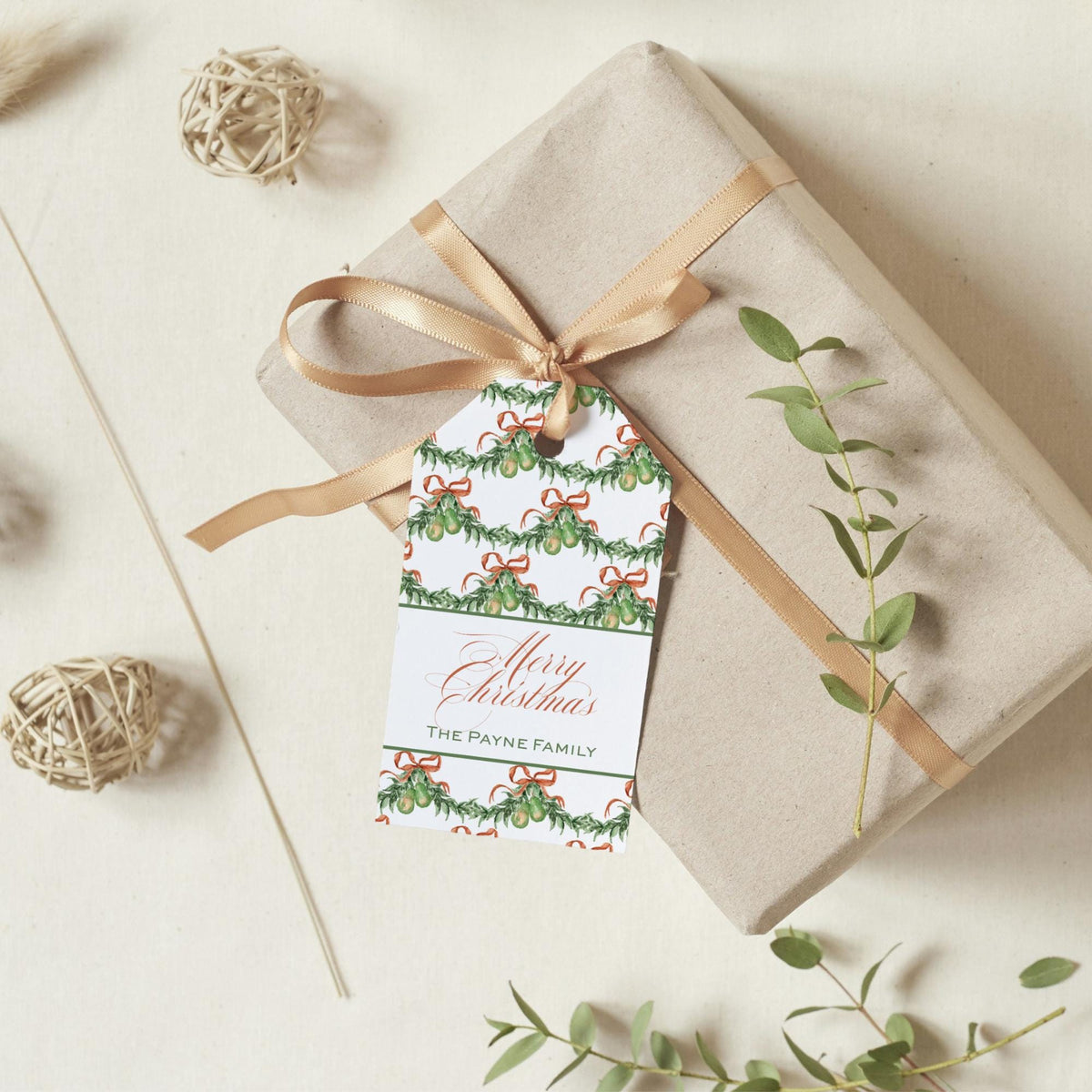A gift box wrapped in brown paper with a gold ribbon, featuring a Christmas-themed tag that reads "Merry Christmas THE PAYNE FAMILY".