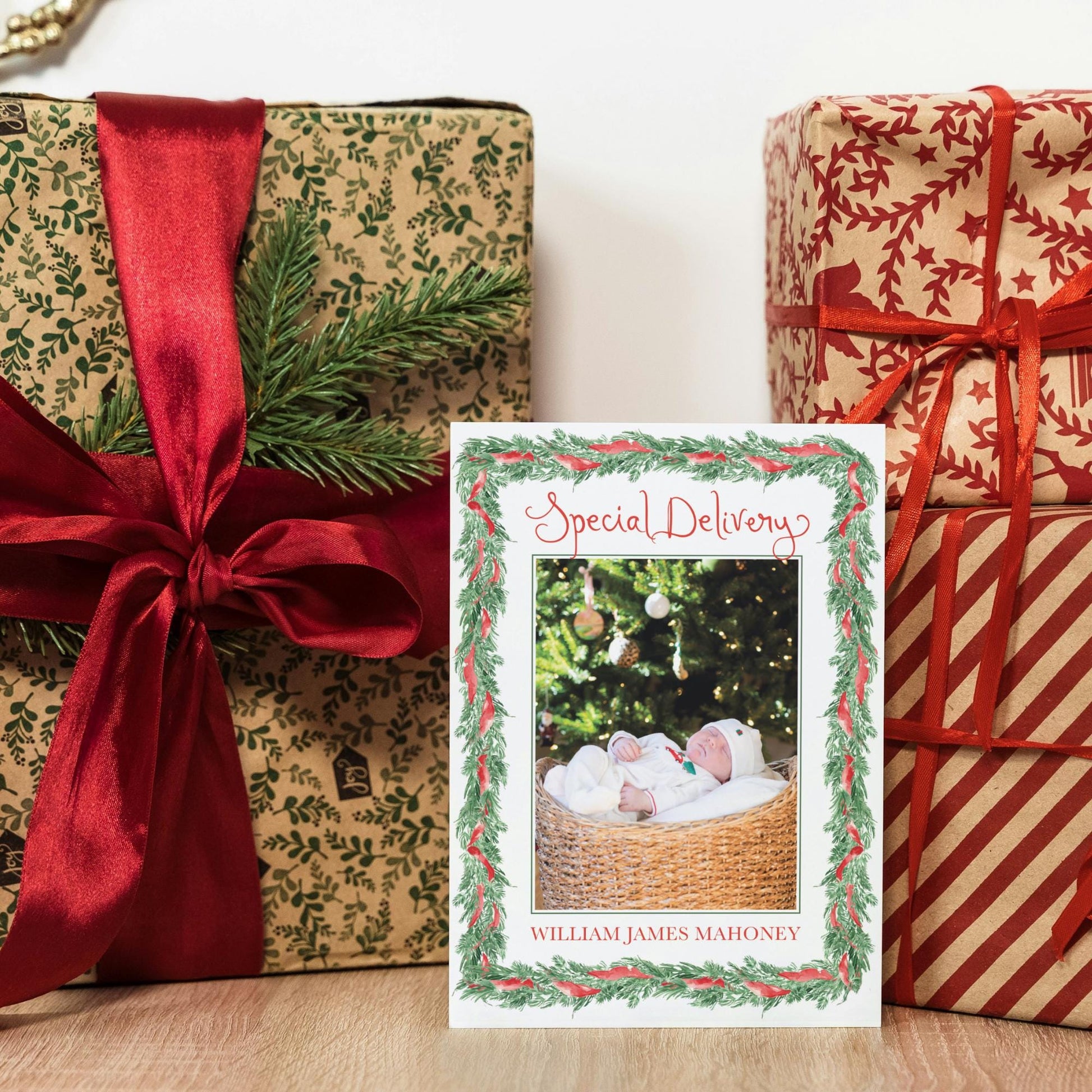a festive scene with a gift box, a card with a photo of a baby, and a stack of wrapped presents.