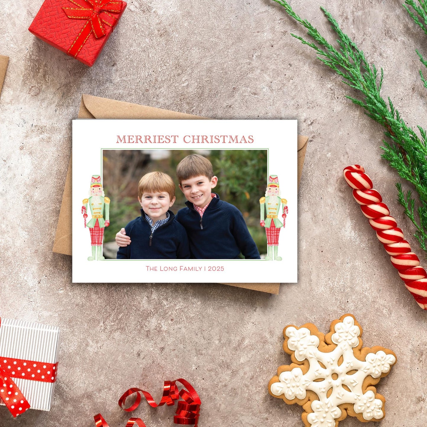 A Christmas card with two children posing for a photo, surrounded by holiday decorations such as a nutcracker, candy cane, and a snowflake.