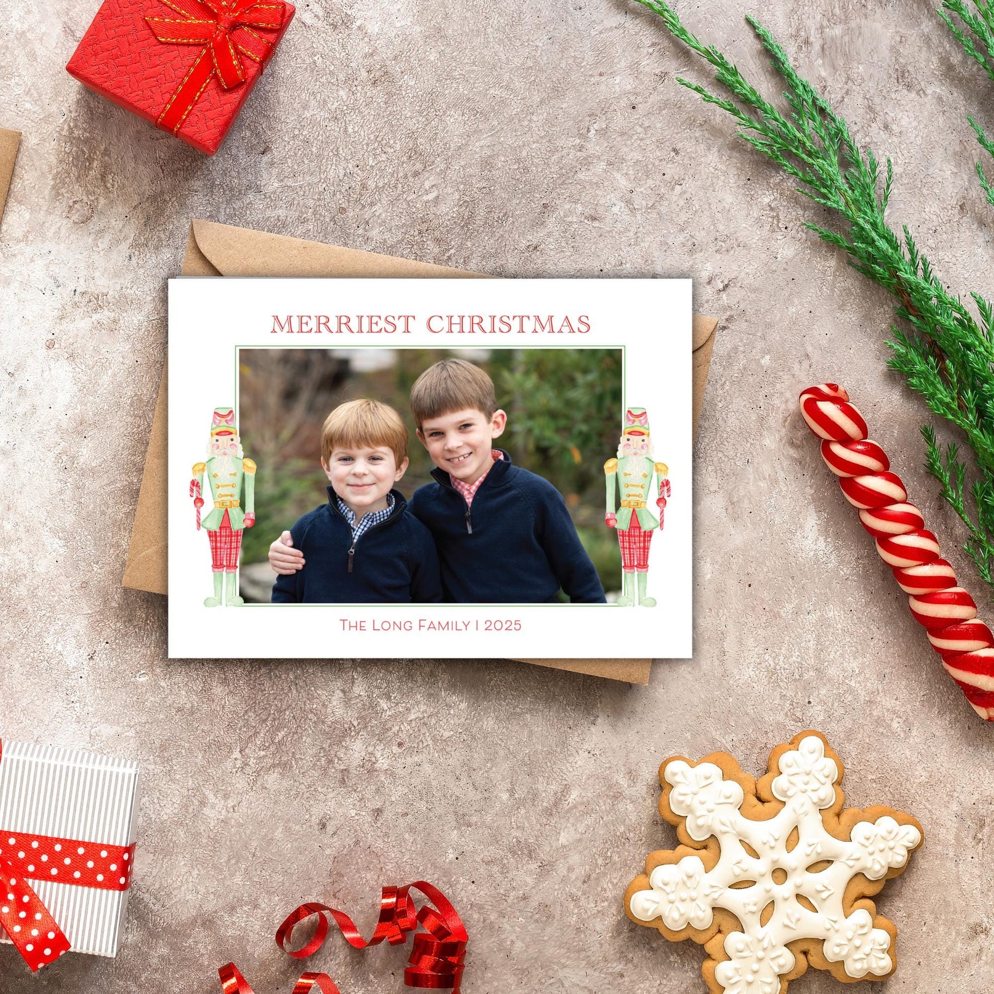 A Christmas card with two children posing for a photo, surrounded by holiday decorations such as a nutcracker, candy cane, and a snowflake.