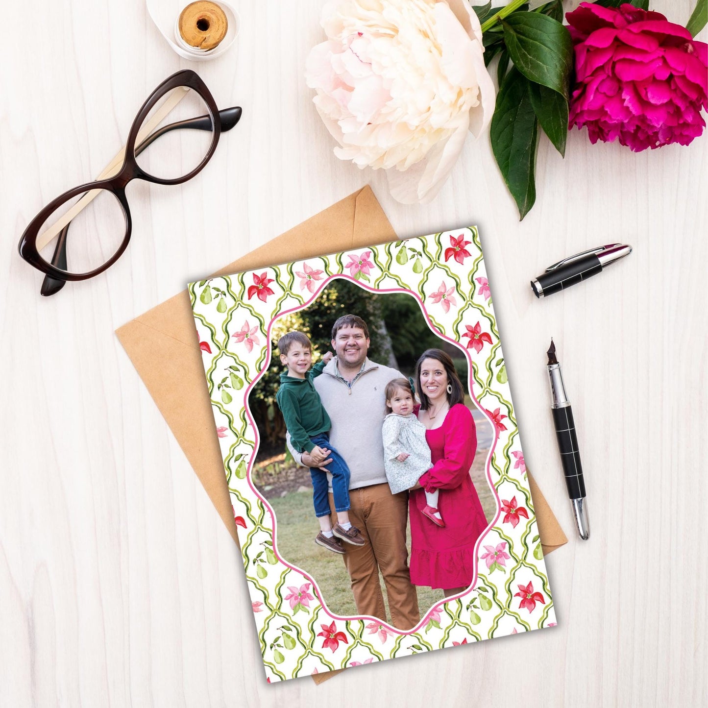 a family portrait of a man, woman, and child, surrounded by flowers and a pen on a white surface.