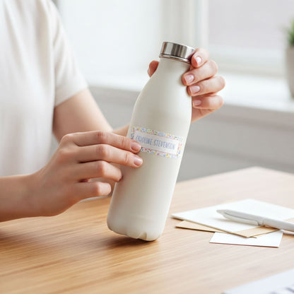 A person's hands holding a white bottle with a label that says "Capsule Stevon" on a wooden table.