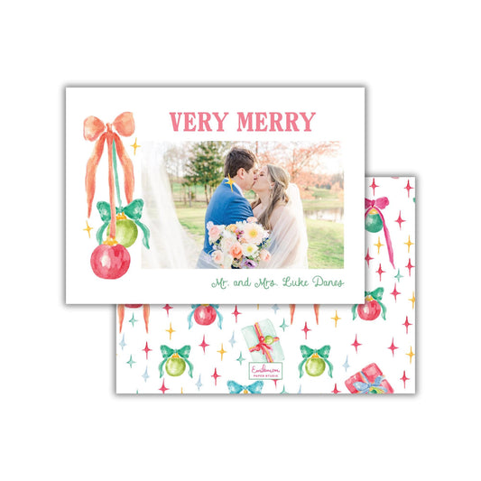 A couple embracing in a romantic moment, surrounded by festive decorations and a &quot;Very Merry&quot; greeting card.