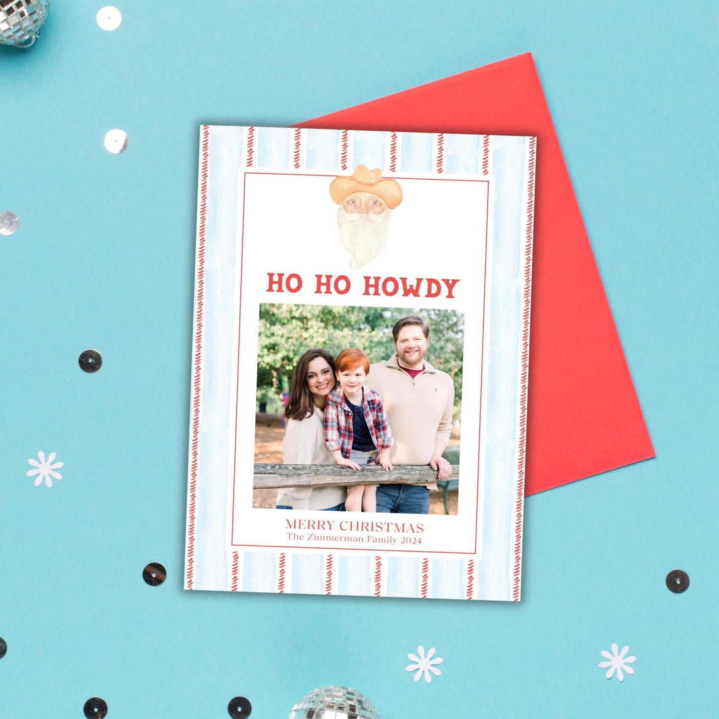 A holiday card with a photo of a family, including a man, woman, and child, along with the text &quot;HO HO HOWDY&quot; and &quot;MERRY CHRISTMAS The Zimmerman Family 2023&quot;.