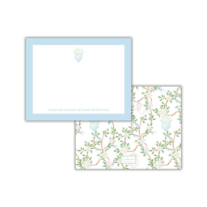 two pieces of paper with different designs. The top paper has a plain white background with a blue border and a small illustration of a flower. The bottom paper has a floral pattern with green leaves and branches.