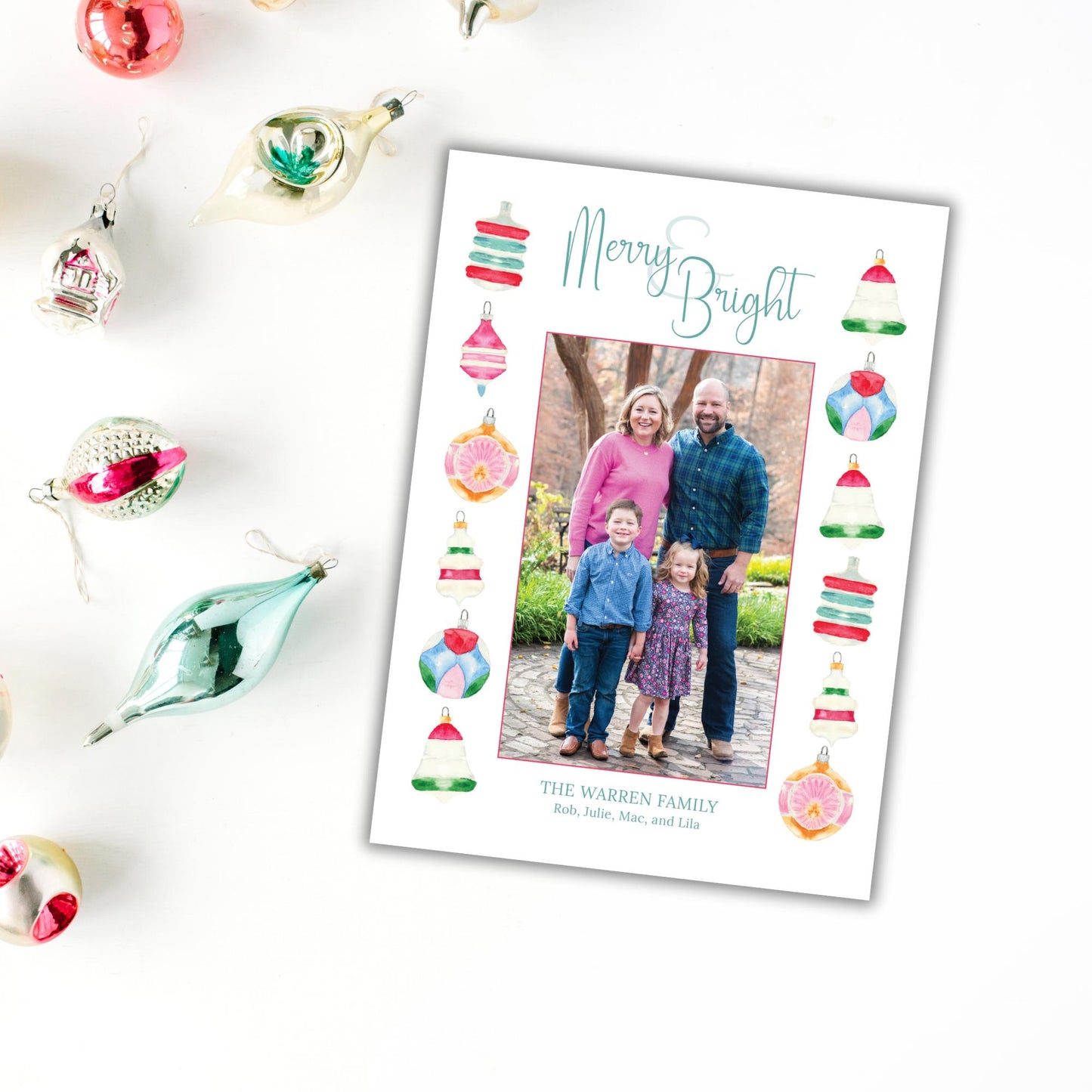 A family photo is displayed on a white card with Christmas ornaments surrounding it, indicating a holiday celebration.