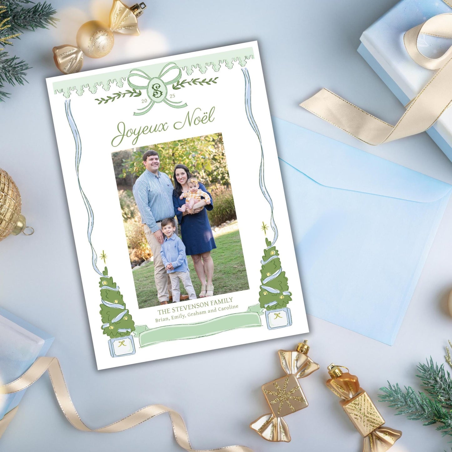 A family photo is displayed on a card surrounded by Christmas decorations, including ornaments, ribbons, and a gift box.
