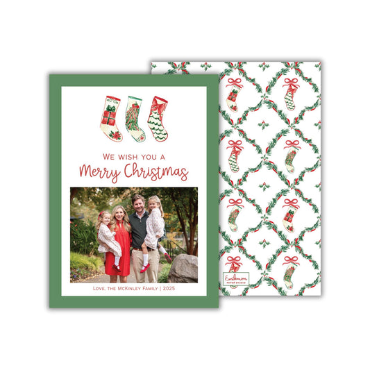 A Christmas card featuring a family photo and a patterned background with Christmas stockings and greenery.