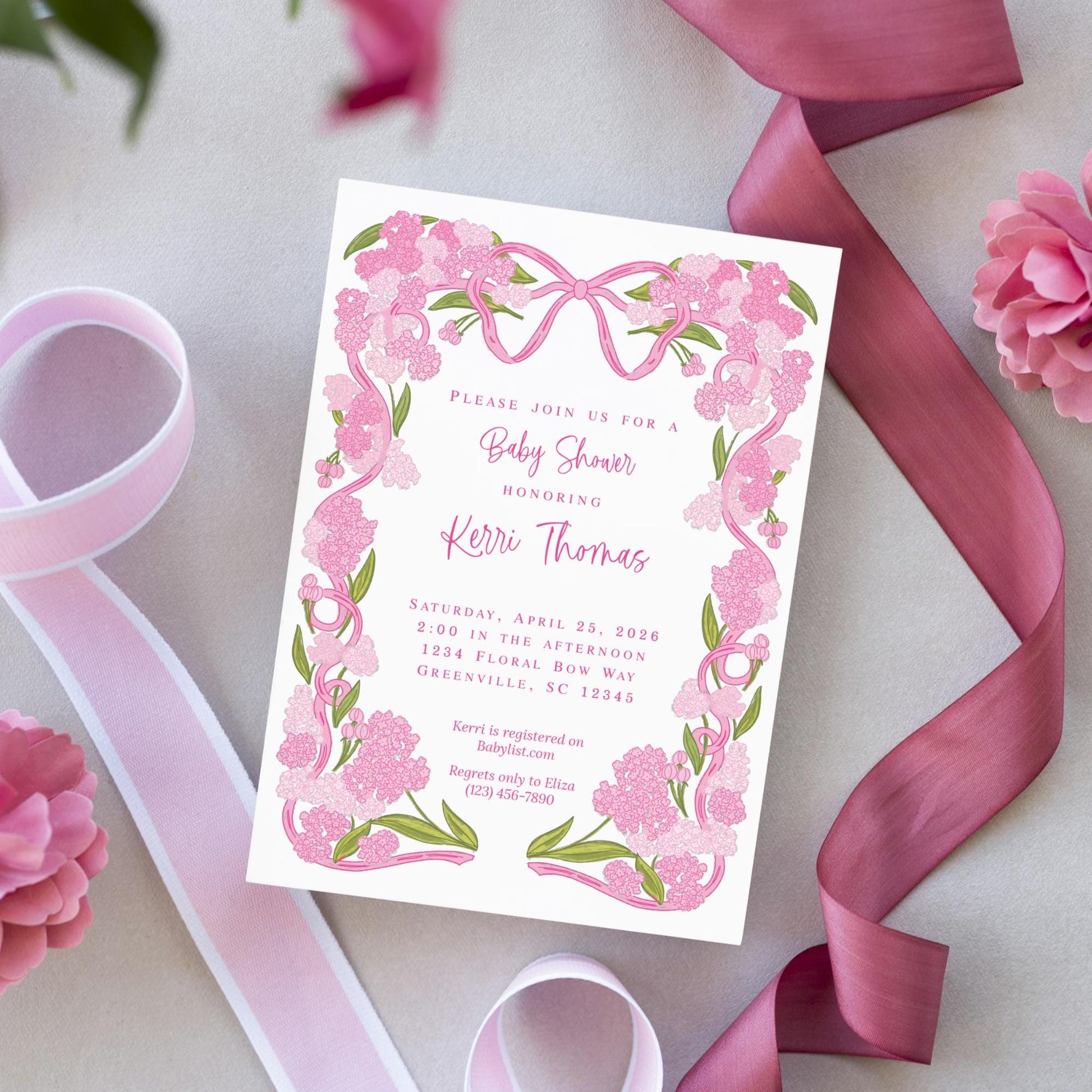 A pink and white baby shower invitation with a floral design and a pink ribbon.