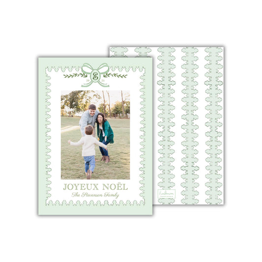A family photo of a man, woman, and child in a park setting, with the text &quot;JOYEUX NOÉL The Revenger Family&quot; displayed on the card.