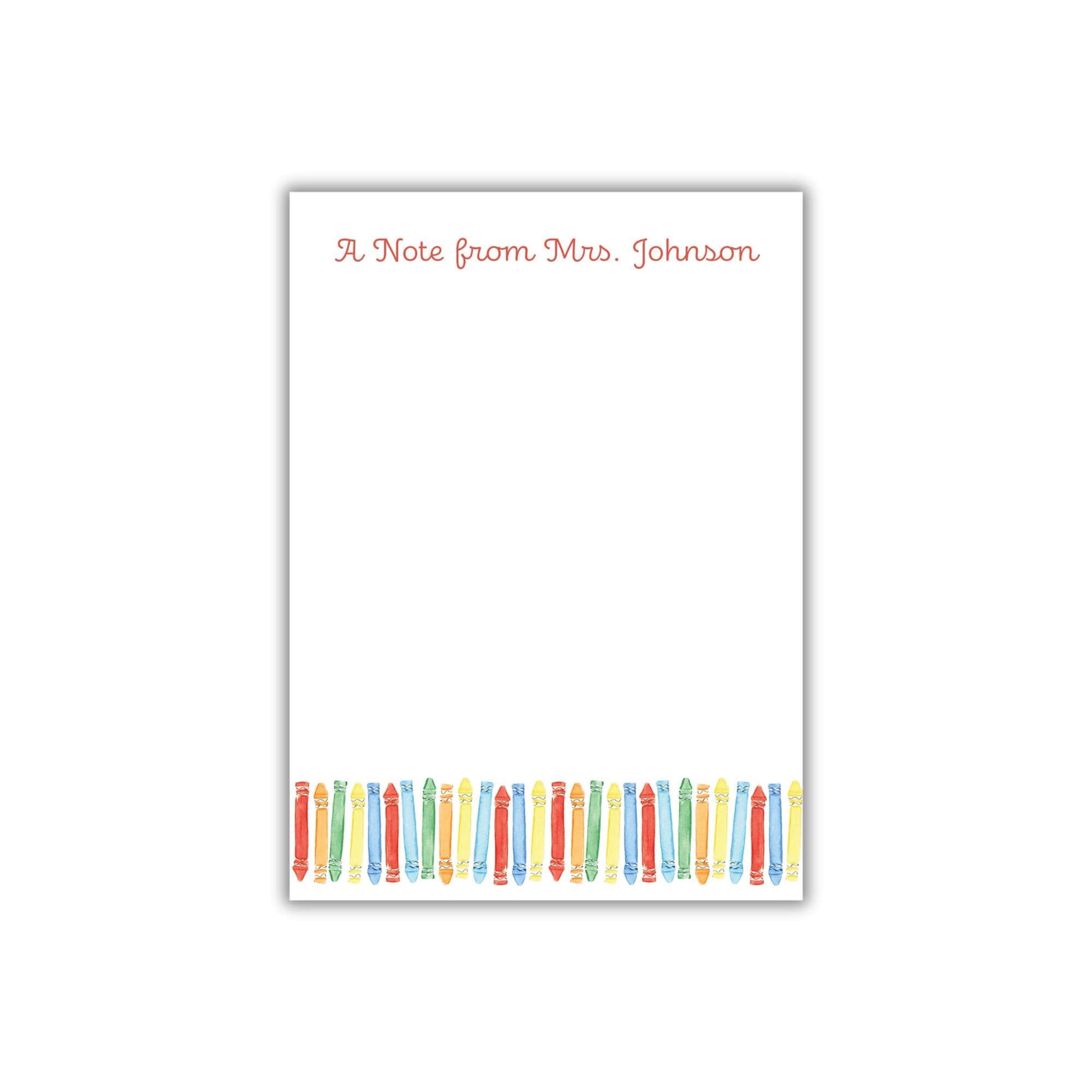 A blank white note card with a border of colored pencils arranged in a row.