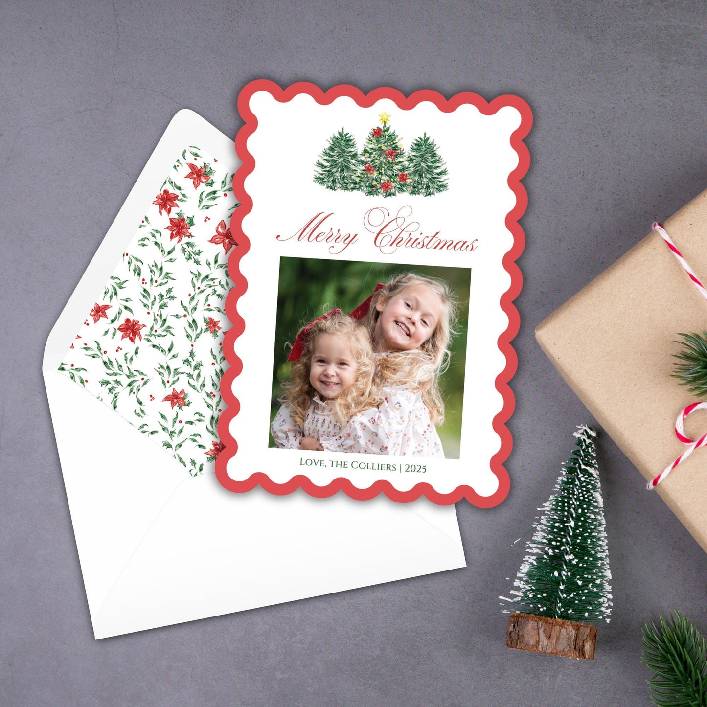A Christmas card with a photo of two young girls, surrounded by holiday decorations such as a small Christmas tree and a gift box.