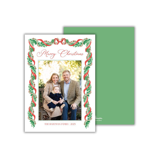 A family portrait of a man, woman, and child, with a festive holiday theme, is displayed on a white card with a green border.