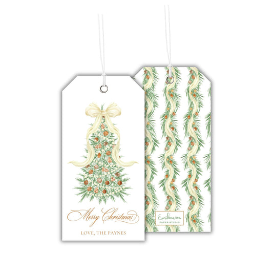 two white tags with Christmas-themed designs hanging from strings. The tag on the left has a Christmas tree design with a bow, and the tag on the right has a repeating pattern of green and white leaves.