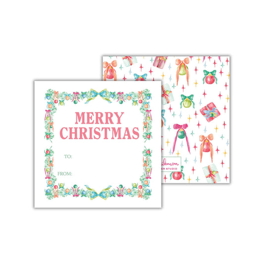 a white square with a floral border and a pink text that reads "MERRY CHRISTMAS TO: FROM:". The square is set against a background with a repeating pattern of Christmas-themed illustrations, including presents, trees, and stars.