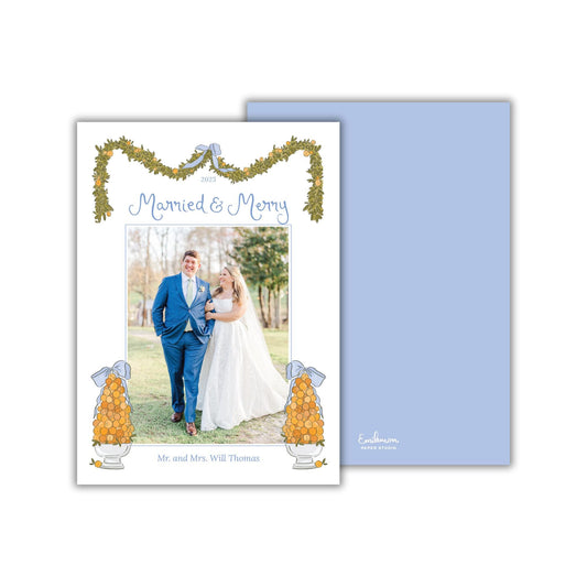 A wedding invitation card featuring a couple standing together in a field, with a decorative border and text.