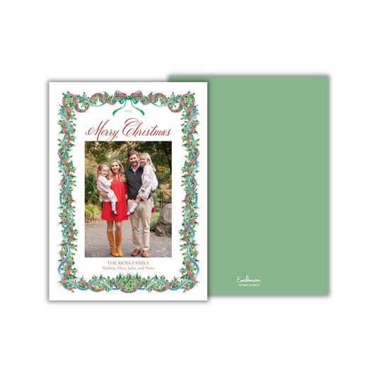 A Christmas card featuring a family photo of a man, woman, and two children, surrounded by a decorative border with holly leaves and berries.