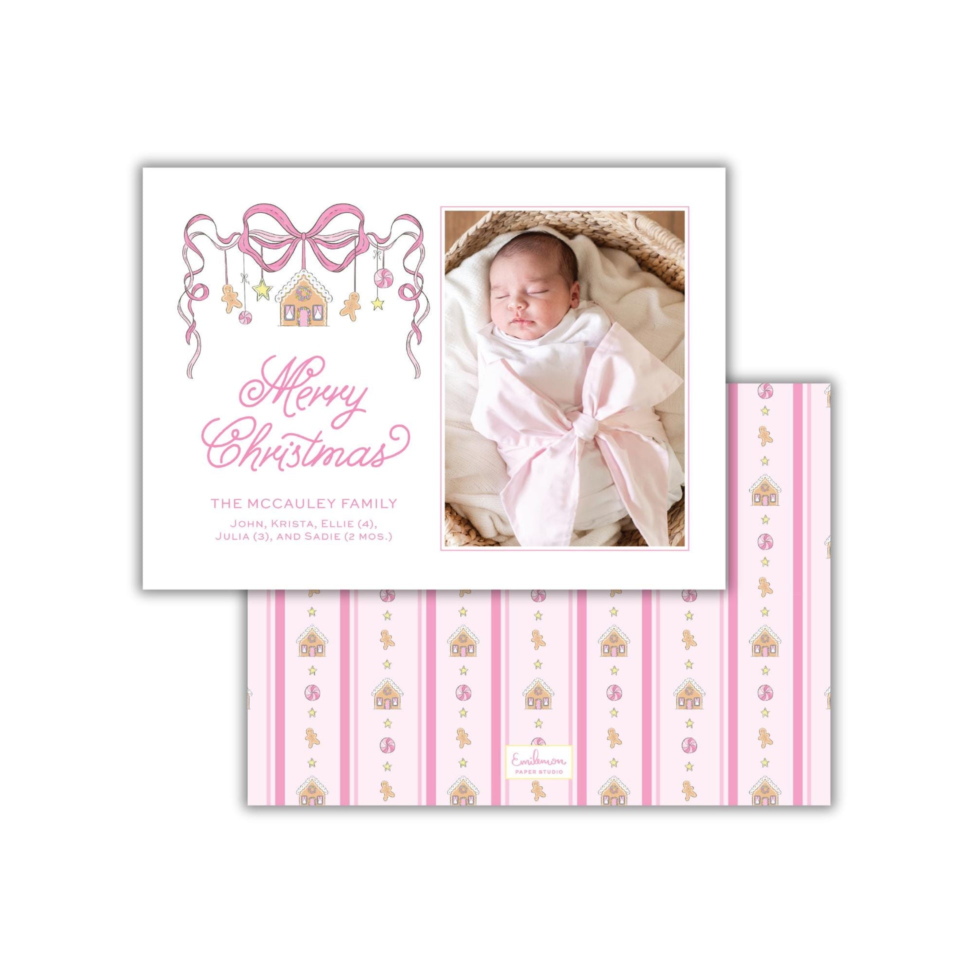 A white card with a photo of a baby swaddled in a pink blanket, along with a decorative bow and the text "Merry Christmas" and "The McCauley Family" written on it.