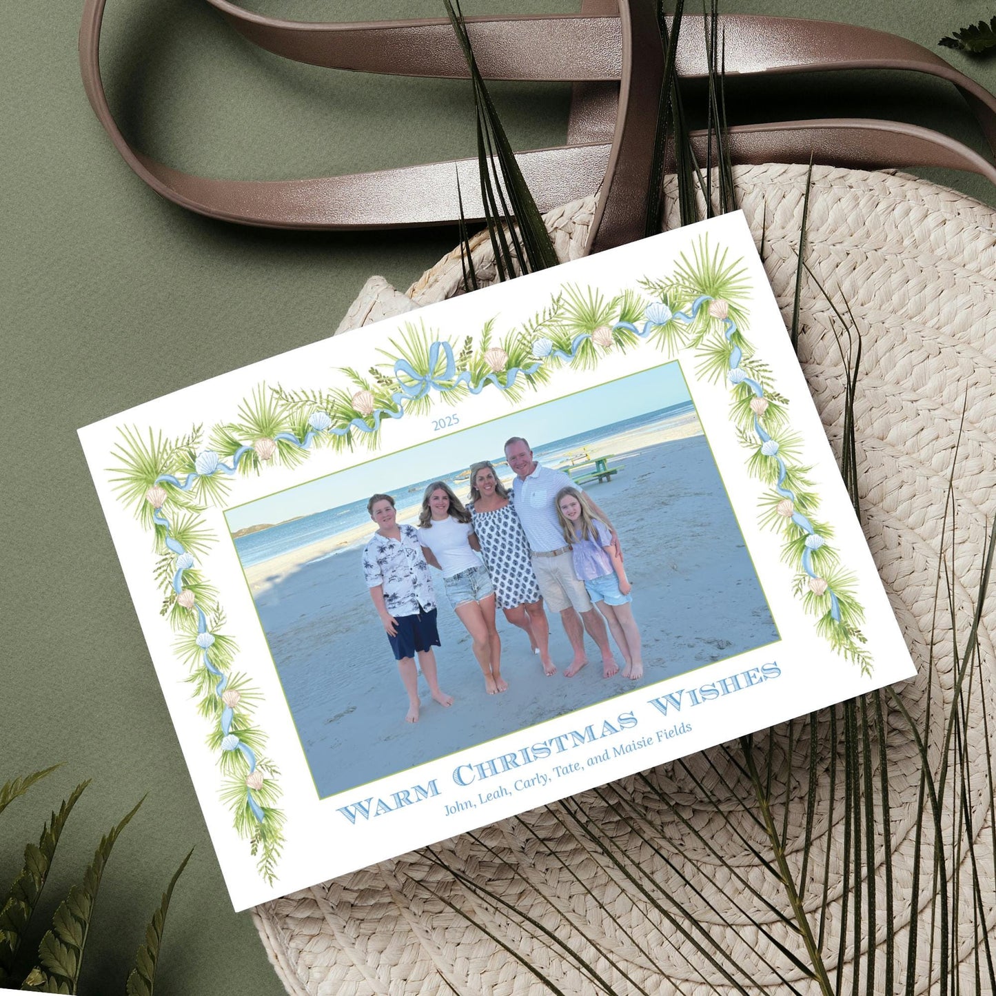 A family photo is displayed on a card with a tropical-themed border, surrounded by a straw hat and other natural elements.