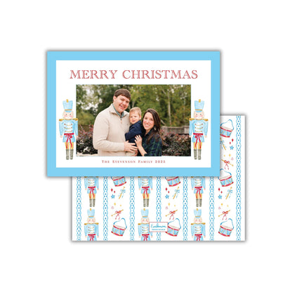 A family photo is displayed in a blue frame, with the text "MERRY CHRISTMAS" written above it. The frame also features nutcracker characters and a pattern of nutcrackers and other Christmas-themed elements.