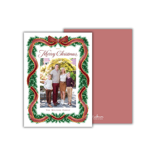 A Christmas card featuring a family portrait of a man, woman, and two children, surrounded by a festive wreath and red ribbon.